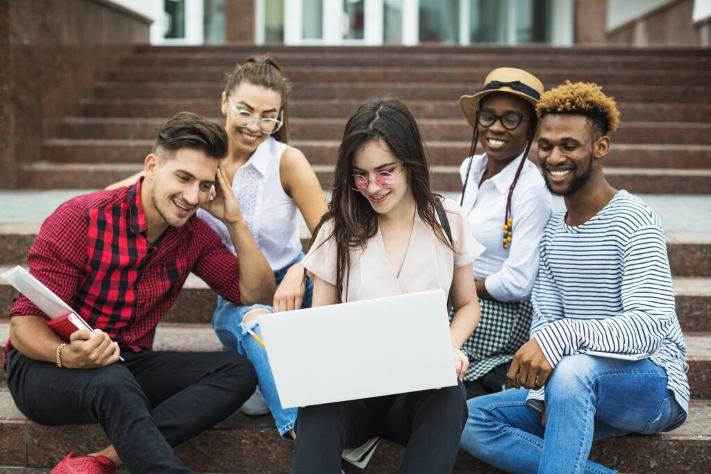 Group of five students holding laptop on the stairs