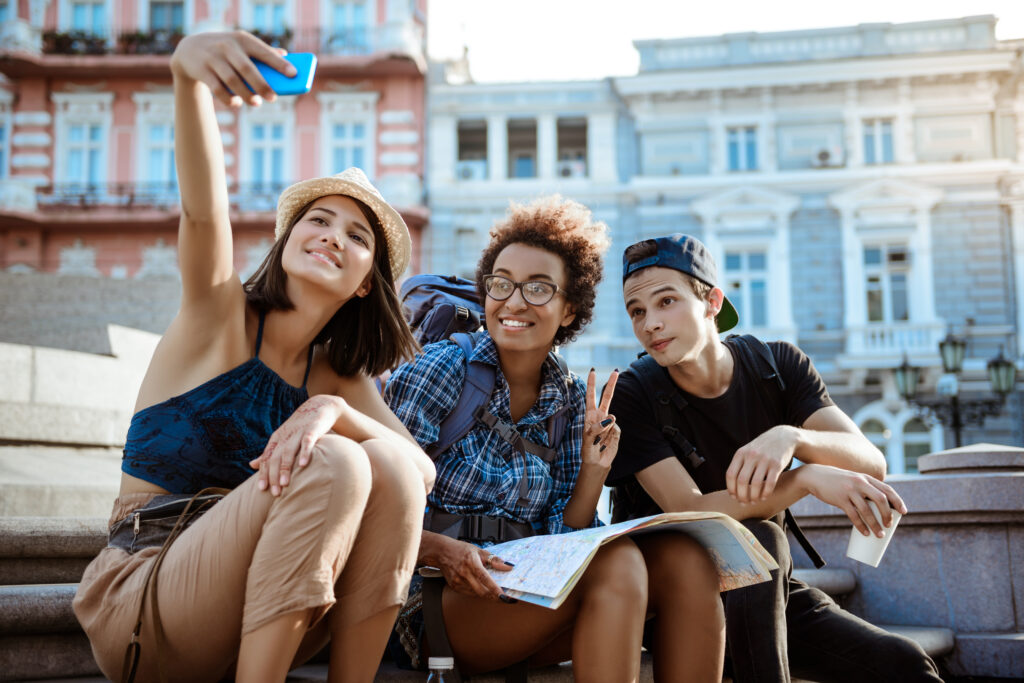 Three friends taking selfie while reading outside